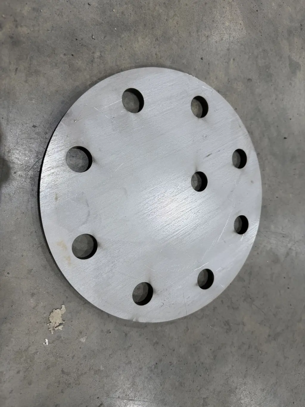Close-up of an actual round metal plate with a custom hole pattern from the Rapid CNC Parts shop.